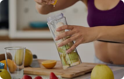 woman in sport-top makes herself bottle of water with fruits and lemon juice